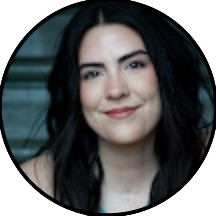 A woman with long dark hair and fair skin is smiling slightly, facing the camera. The background is blurred, capturing a moment reminiscent of the warmth seen in the smile doctor reviews.